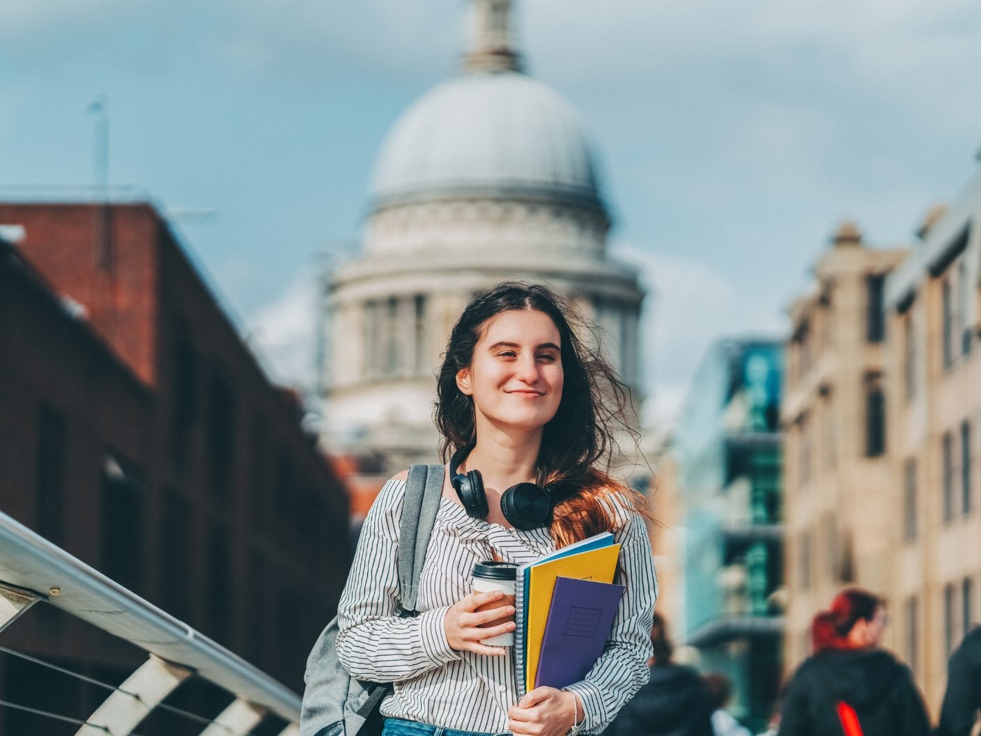 Female student smiling and walking in London with books